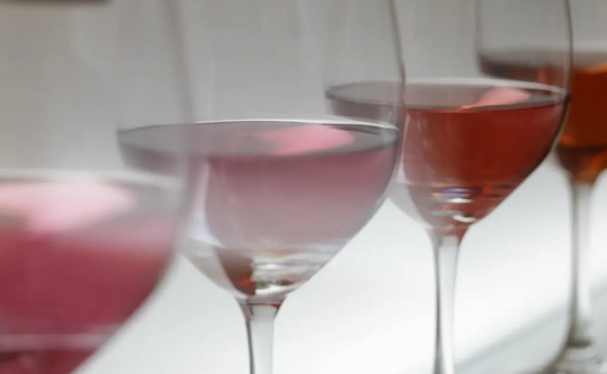 Close-up of various wine glasses filled with rosé in soft lighting, perfect for wine tasting events.
