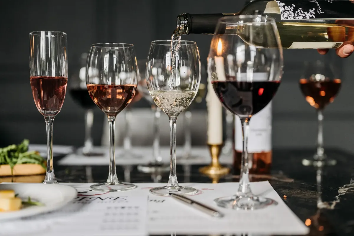 Elegant wine tasting setup with various wines being poured into glasses indoors.