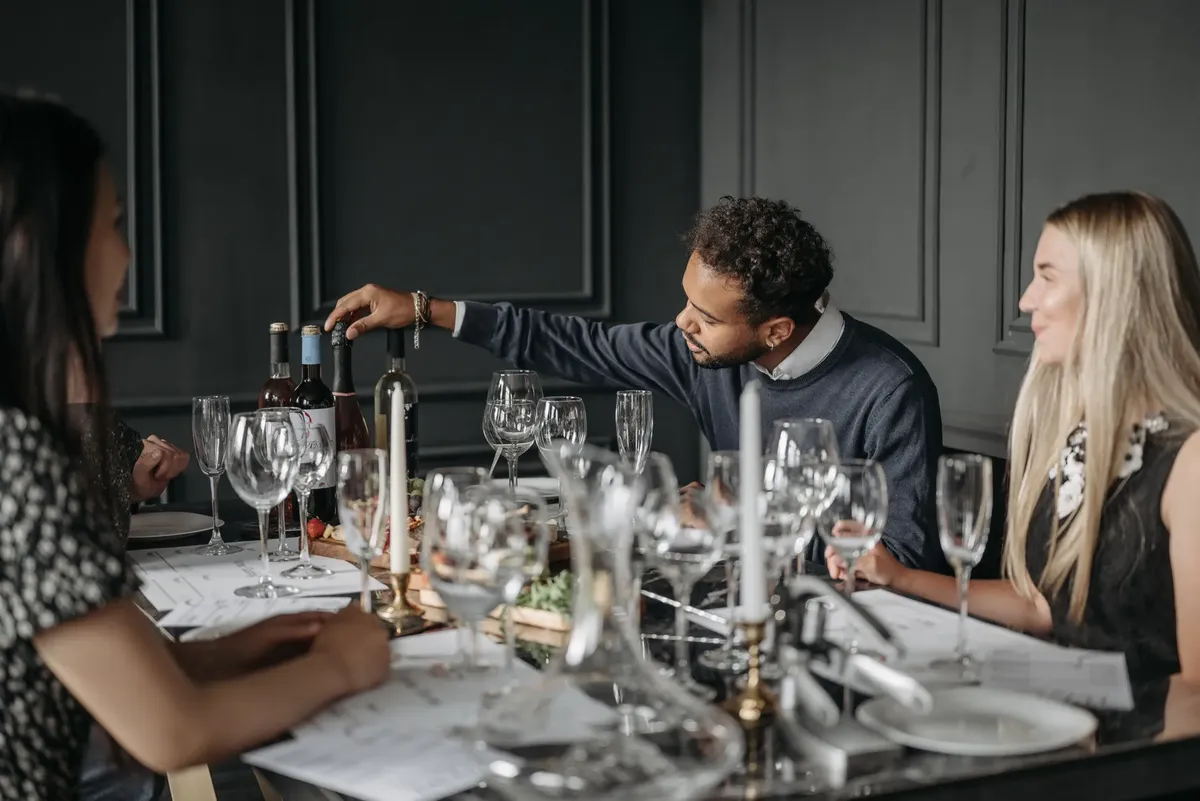 A diverse group of adults enjoying a dinner party indoors with wine and candles.