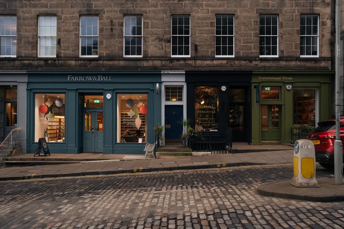 Charming shopfronts in Edinburgh at dusk featuring Farrow & Ball and Communique Wines.